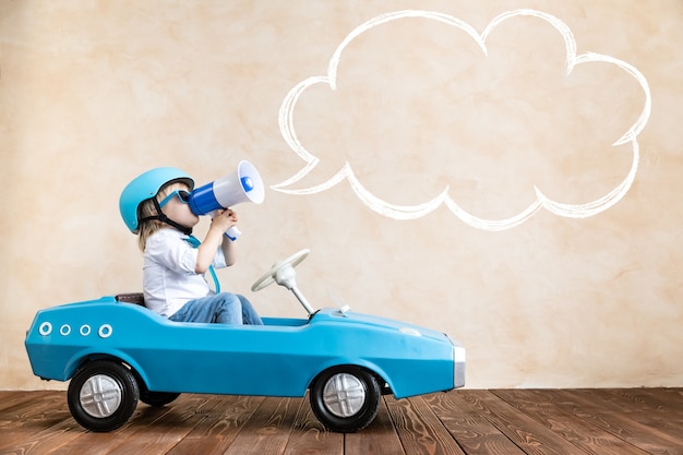 Photo enfant drôle conduisant une voiture de jouet à l'intérieur.