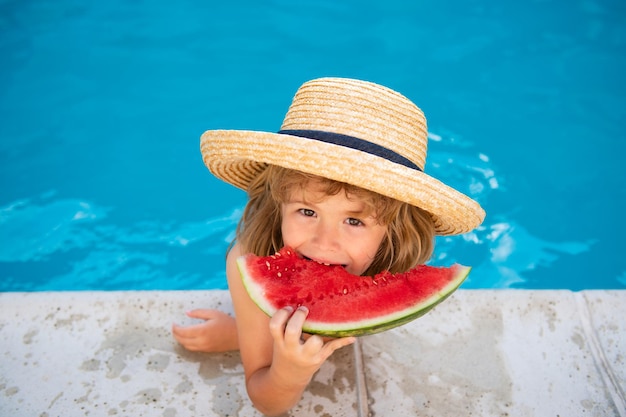 L'enfant drôle joue dans la piscine l'enfant mange une pastèque douce profitez de l'enfance insouciante de l'été