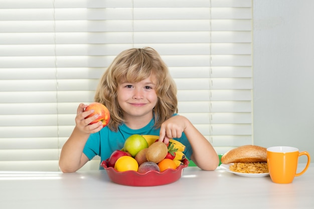 Enfant drôle mangeant une pomme portrait d'un enfant préadolescent mangeant de la nourriture fraîche et saine dans la cuisine à la maison