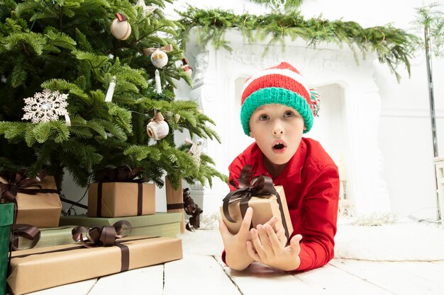 Enfant drôle à Noël Garçon sous le sapin de Noël avec des cadeaux