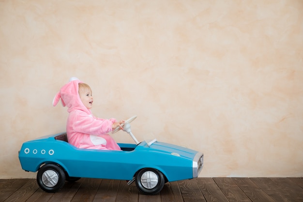 Enfant drôle portant le lapin de Pâques. Voiture jouet enfant à la maison.