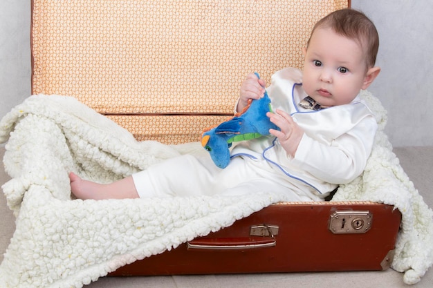 L'enfant drôle s'assied dans une vieille valise