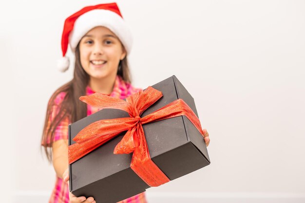 Enfant drôle souriant au chapeau rouge du Père Noël. Tenir le cadeau de Noël à la main. Notion de Noël. sur fond blanc