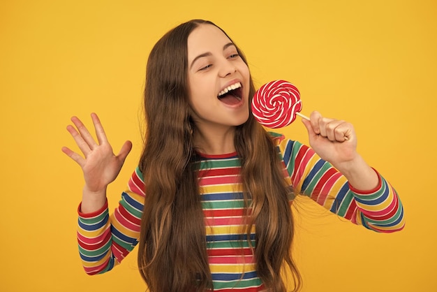 Enfant drôle avec sucette sur fond jaune isolé Douce vie d'enfance Adolescente avec un délicieux magasin de bonbons sucette au caramel Visage excité émotions joyeuses d'une adolescente