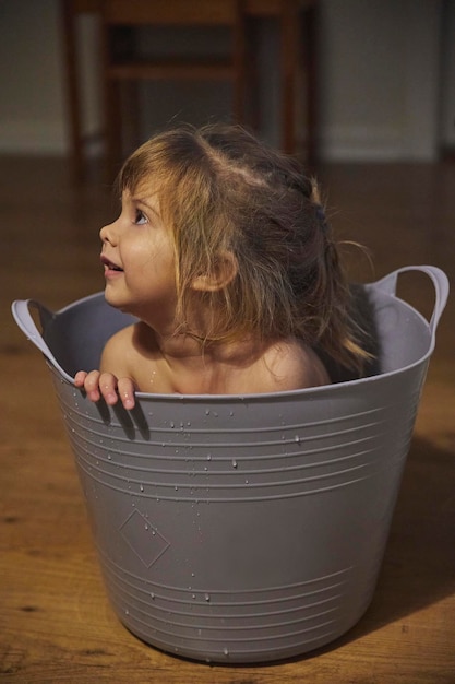 L'enfant avec du charme se baigne dans une petite salle de bains le soir