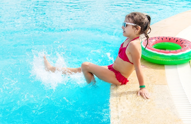 L'enfant éclabousse de l'eau dans la piscine. Gens.