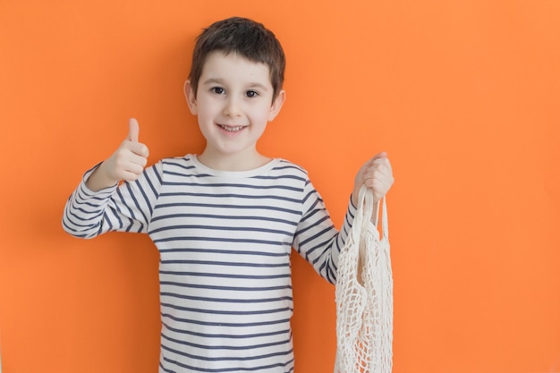 Enfant avec éco sac pouces vers le haut