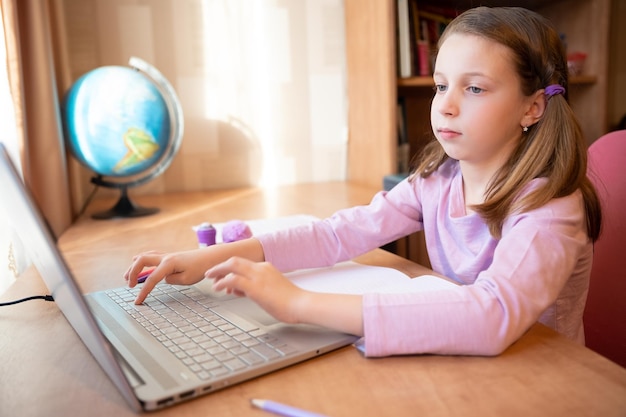 Enfant d'école d'apprentissage à distance en ligne avec ordinateur ayant une conversation par vidéoconférence avec l'enseignant et le groupe de classe