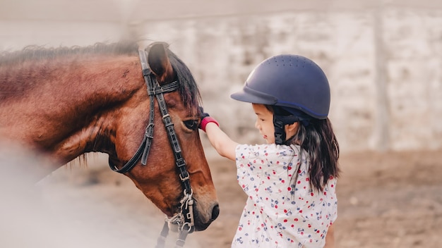 Enfant de l'école asiatique fille avec l'équitation ou la pratique de l'équitation dans un ranch de chevaux