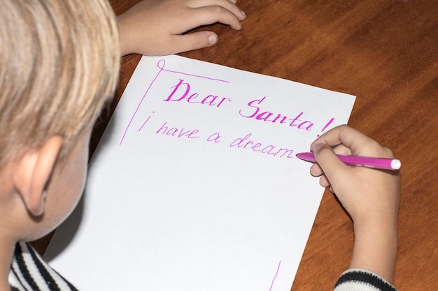 Photo l'enfant écrit sur une feuille de papier blanche de près