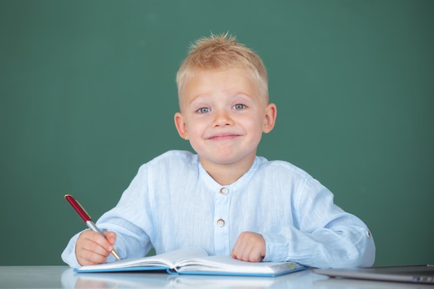 Enfant écrivant dans un cahier en classe portrait d'un drôle d'élève de l'école primaire en classe à l'école