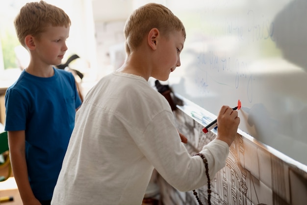 Enfant écrivant sur la vue latérale du tableau blanc