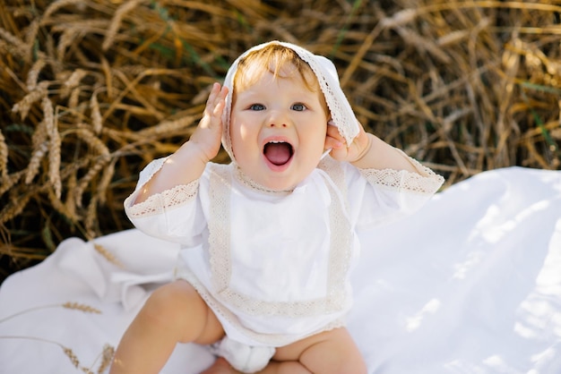 Un enfant émotif un garçon en vêtements blancs se détend à l'air frais dans un champ et tient