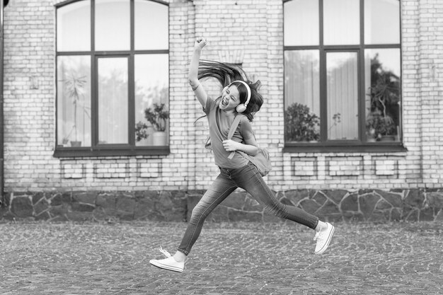 Enfant énergique fille sautant danse écoute musique casque concept de vie active