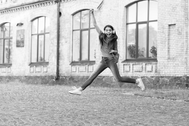 Enfant énergique fille sautant danse écoute musique casque n'arrête jamais le concept