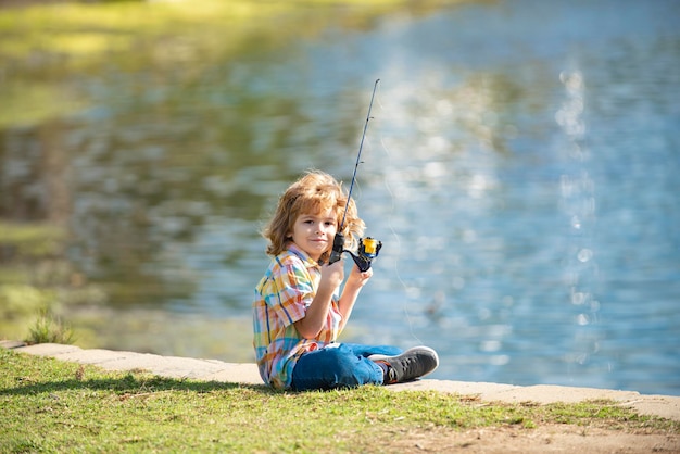 Enfant d'enfance heureux pêchant sur le lac garçon avec spinner au concept de pêche en rivière