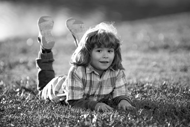 Enfant enfant en plein air dans le parc printemps garçon allongé sur l'herbe été à pied adaptation des enfants