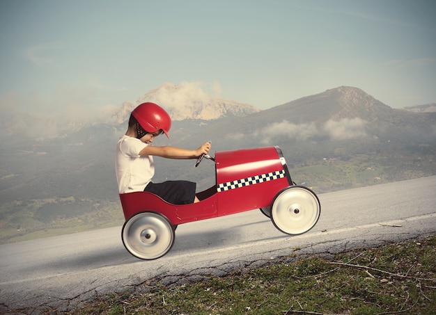 Enfant escalader une montagne avec une petite voiture jouet