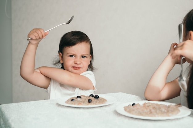 L'enfant est capricieux et refuse de manger. Une petite fille est assise à une table et est en colère