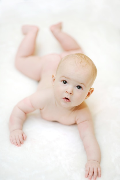 Enfant est couché sur le ventre sur un fond blanc