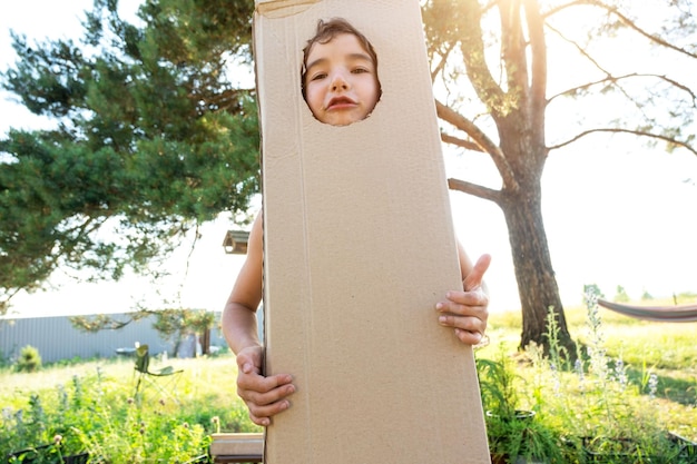 L'enfant est drôle de danser et de s'amuser dans un costume de boîte découpe ronde pour le visage et les mains Déménager dans une nouvelle maison des jeux pour enfants improvisés signifie un costume avec vos propres mains