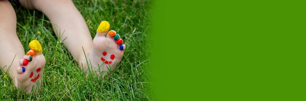 L'enfant était allongé sur l'herbe verte. Souriez avec des peintures sur les jambes et les bras. Enfant s'amusant à l'extérieur dans le parc du printemps. Mise au point sélective. La nature