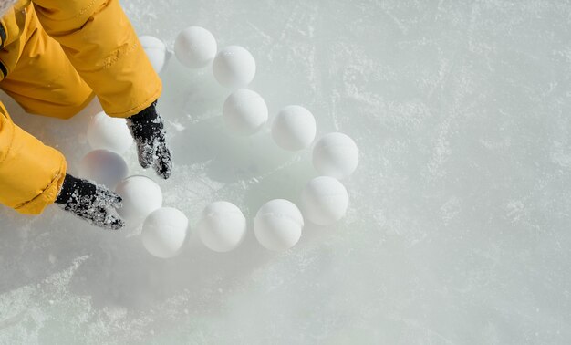 L'enfant étale des boules de neige en forme de cœur sur la patinoire