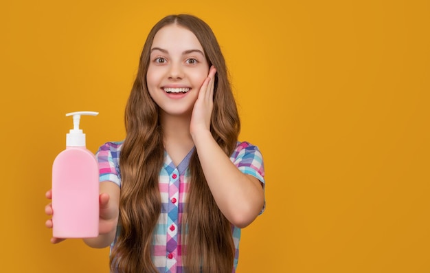 Enfant étonné avec une bouteille de savon liquide sur fond jaune