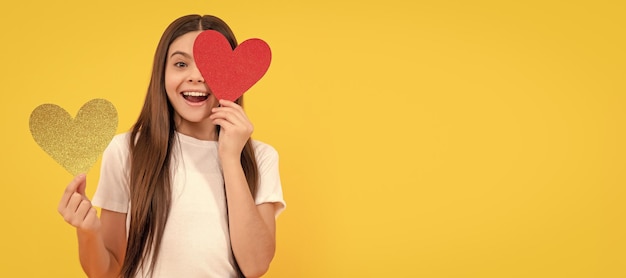 Enfant étonné avec un cœur rouge sur fond jaune Valentine vente portrait de fille enfant avec un cœur d'amour