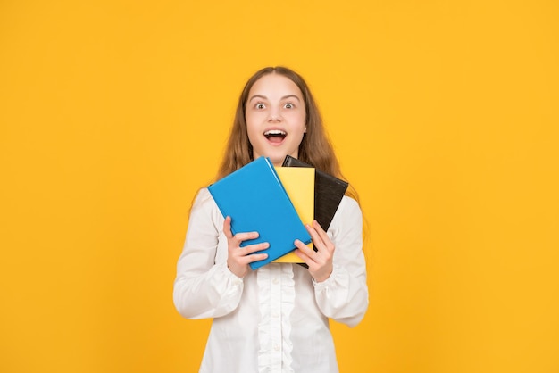 Un enfant étonné tient un livre scolaire sur une étude de fond jaune