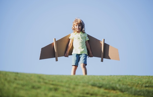 Enfant d'être enfant pilote avec des ailes de papier battant les vacances d'été et le concept de voyage drôle d'enfant garçon wit