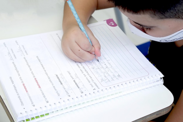 Enfant étudiant dans une salle de classe avec des livres et des cahiers sur la table