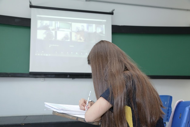 Enfant étudiant dans une salle de classe avec des livres et des cahiers sur la table