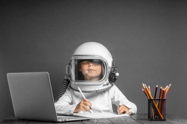 L'enfant étudie à distance à l'école, portant un casque d'astronaute. retour à l'école