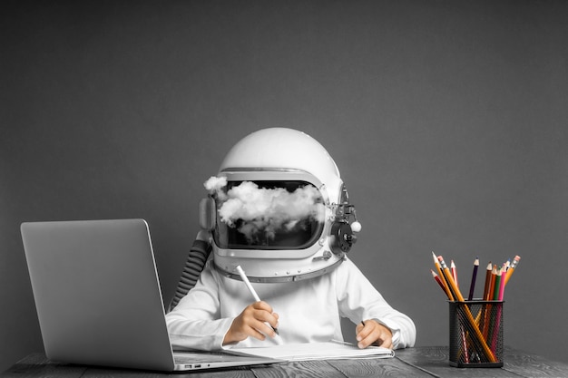 Photo l'enfant étudie à distance à l'école, portant un casque d'astronaute. retour à l'école