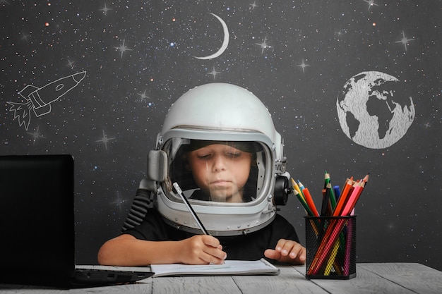 L'enfant étudie à distance à l'école, portant un casque d'astronaute. retour à l'école