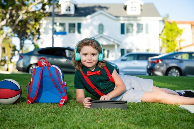 Un enfant étudie en ligne en plein air dans un parc étudie dans des cours d'école en ligne dans la nature