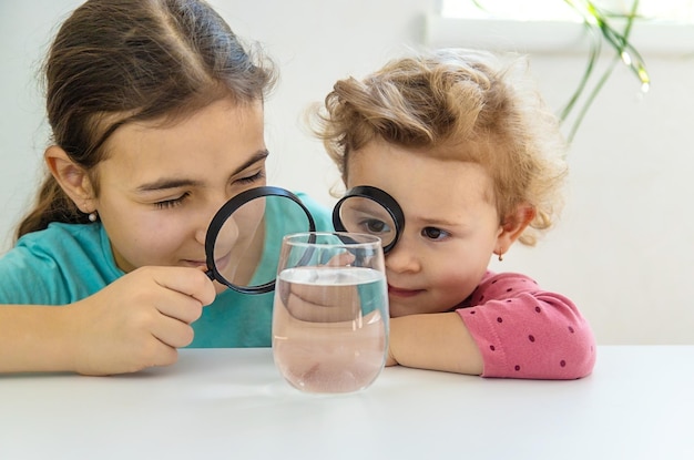 L'enfant examine l'eau sous une loupe Mise au point sélective