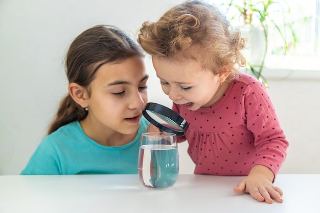 L'enfant examine l'eau sous une loupe Mise au point sélective