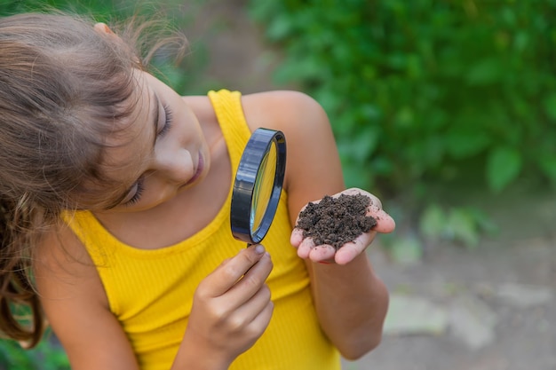 L'enfant examine le sol avec une loupe. Mise au point sélective.