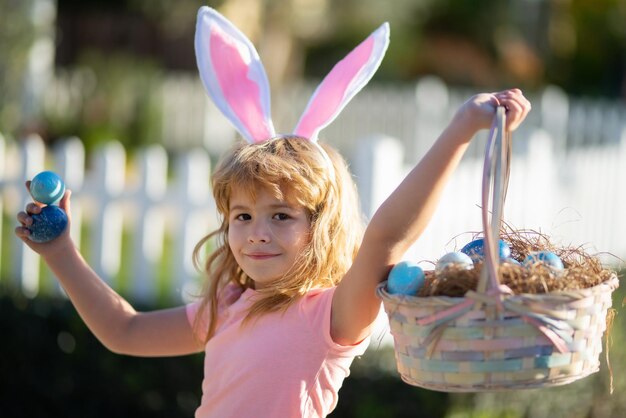 Enfant excité avec panier de Pâques Lapin de Pâques enfant garçon avec un visage mignon Enfants chassant les oeufs de Pâques Joyeuses fêtes de Pâques