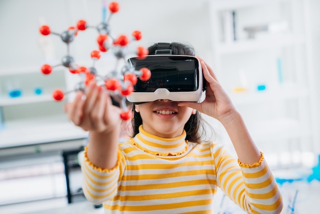Un enfant explore des modèles moléculaires avec des lunettes VR Une fille porte un casque de réalité virtuelle