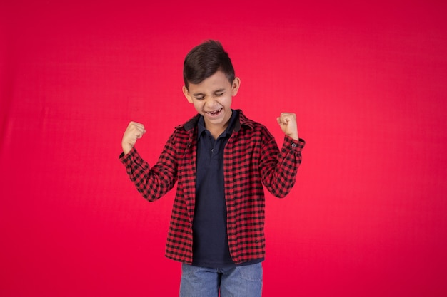 Enfant avec des expressions faciales dans une photo de studio sur fond rouge.