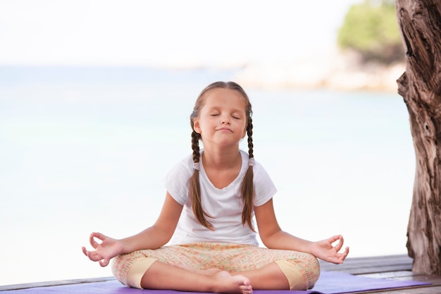 Enfant faisant de l'exercice sur la plate-forme à l'extérieur. Mode de vie sain dans l'océan. Fille de yoga