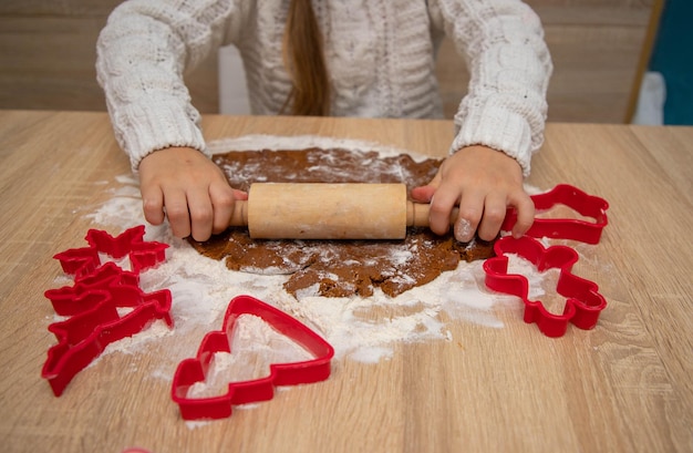 L'enfant fait des biscuits de Noël à partir de pâte à pain d'épice et d'emporte-pièces. Concept de carte de Noël.