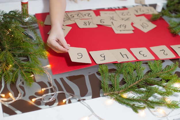 un enfant fait un calendrier de l'avent fait à la main en carton pour les vacances d'hiver en famille pour le nouvel an