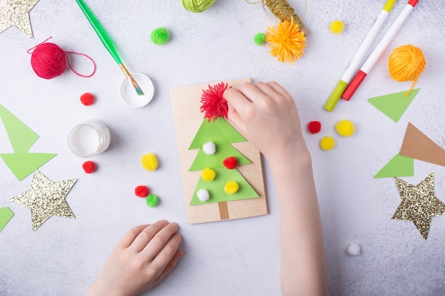 L'enfant fait une carte de voeux collage de papier de noël enfants projet d'art artisanat pour enfants photo de haute qualité