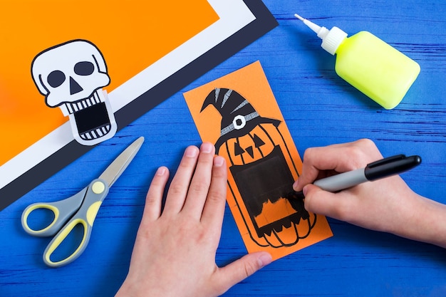 L'enfant fait le crâne et la Jackolantern de jouets en papier à pleines dents pour Halloween