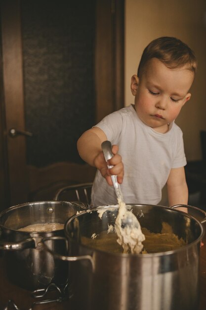 l'enfant fait cuire la nourriture à la table dans la cuisine