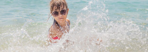 L'enfant fait des embruns sur la mer.